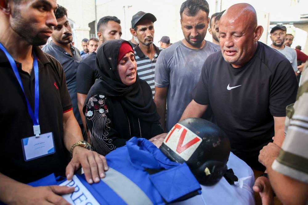 Friends and relatives mourn over the body of Al-Aqsa TV photojournalist Muhammad al-Tanani, who was killed during Israeli bombardment in the northern Gaza Strip, as he is prepared for burial at Al-Ahli Arab hospital on Wednesday. AFP