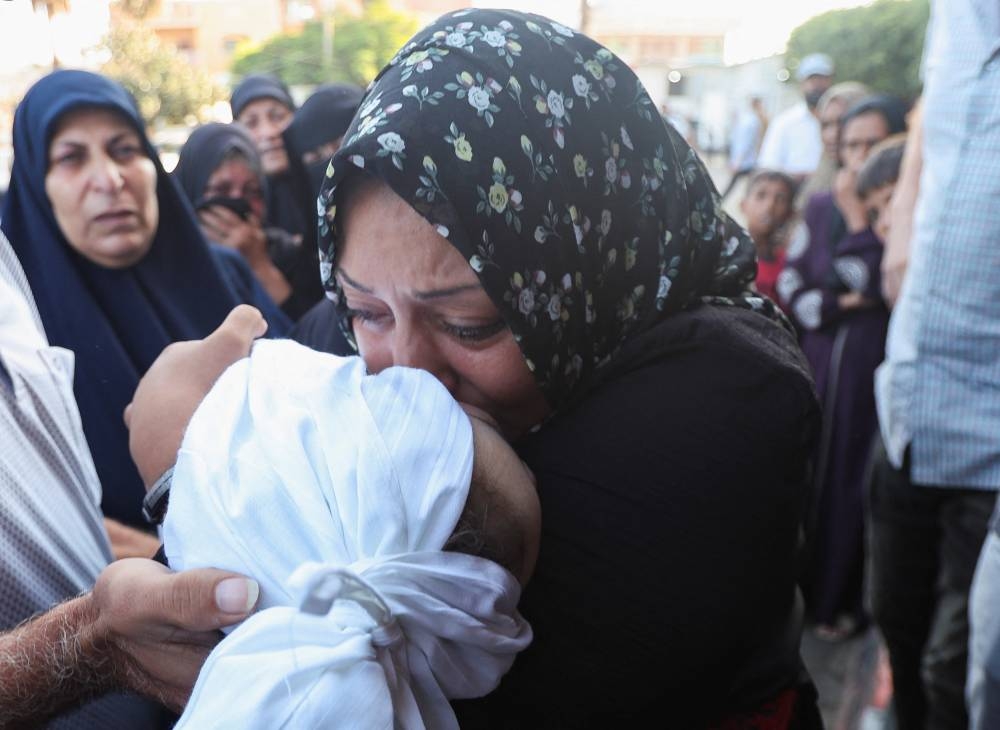 A Palestinian woman kisses the body of a child who was killed in an Israeli strike, at Al-Aqsa Martyrs Hospital in Deir Al-Balah in the central Gaza Strip, on Wednesday. REUTERS