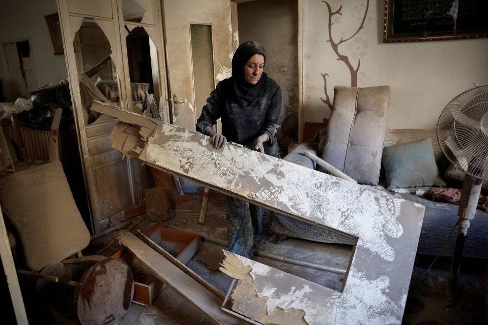 Maha Haddad, mother-in-law of Ahmed Al-Khatib cleans rubble in their damaged apartment at the strike site in Beirut, on Friday. REUTERS