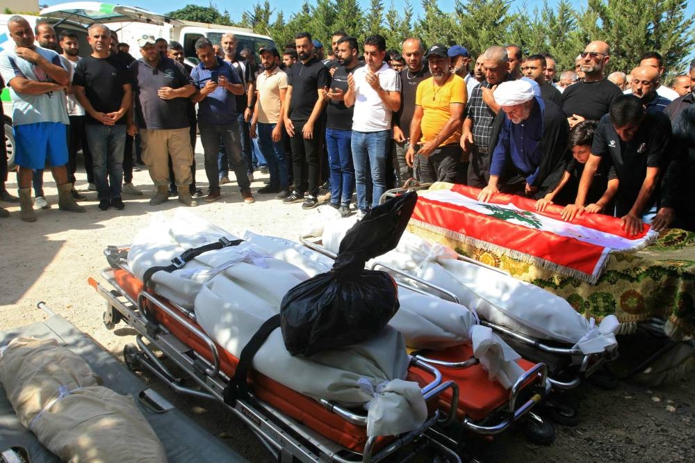 Mourners pray over the shrouded bodies of five people killed in an Israeli airstrike that targeted the southern Lebanese village of Bazuriyeh a day earlier, ahead of their funeral on Saturday. AFP