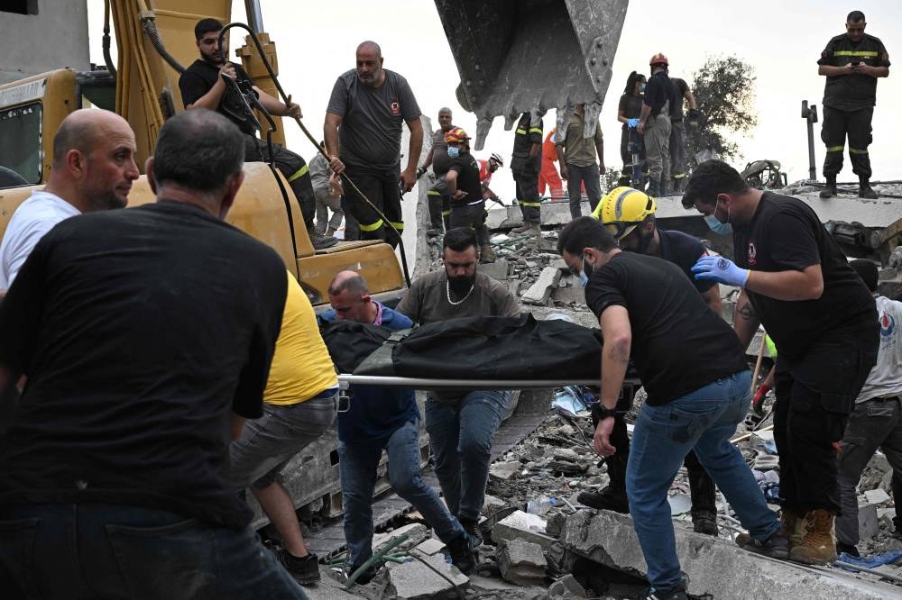 Lebanese civil defence workers transport a body after it was unearthed from under the rubble at the site of an Israeli airstrike on the Mount Lebanon village of Maaysra, east of the coastal town of Byblos on Saturday. AFP