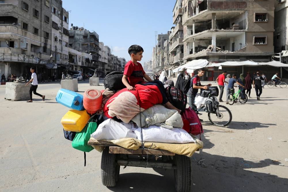 A displaced Palestinian boy sits on a cart as he and others make their way to flee areas in the northern Gaza Strip in Gaza City on Saturday. REUTERS