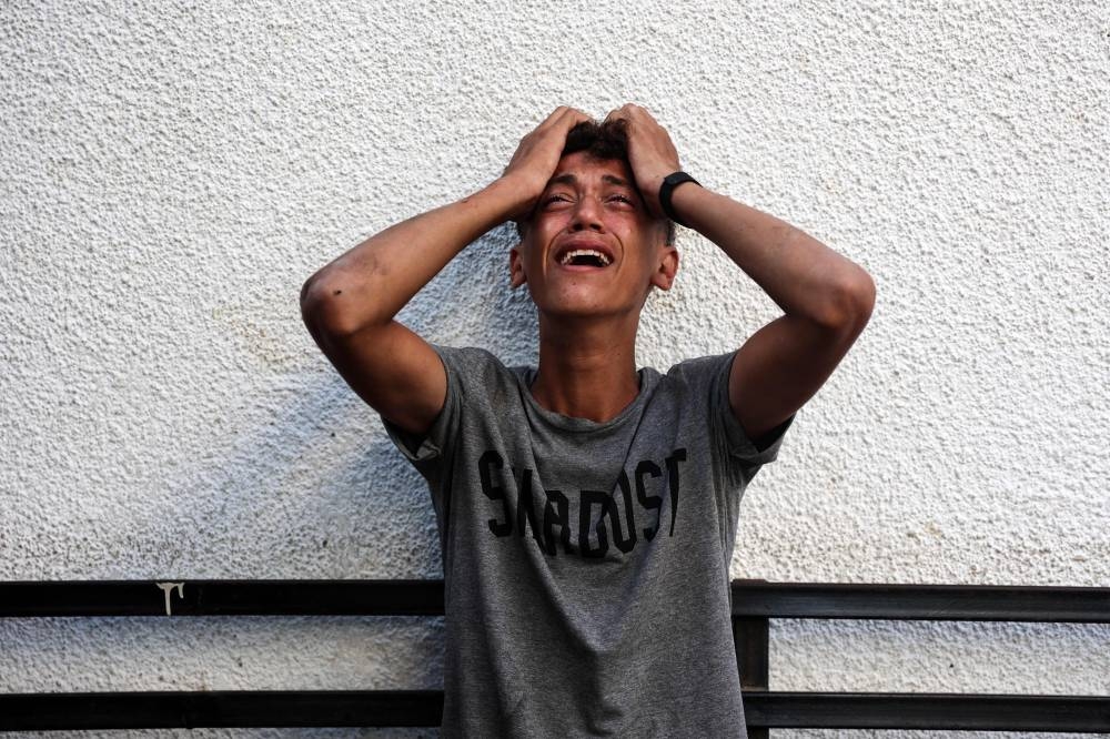 A Palestinian youth reacts upon seeing the bodies of relatives killed in an overnight Israeli airstrike in the Jabalia refugee camp in the northern Gaza Strip, in front of the al-Maamadani on Saturday. AFP