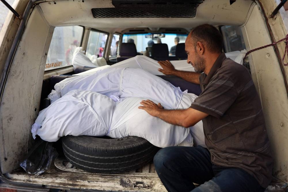 A man mourns over the bodies of a relatives killed in an overnight Israeli airstrike in the Jabalia refugee camp in the northern Gaza Strip, mourns near the bodies of his relatives in front of the al-Maamadani on Saturday. AFP