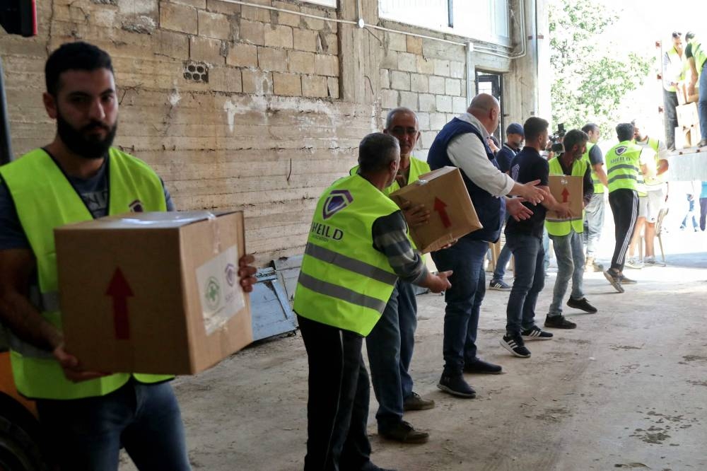 Volunteers unload humanitarian aid provided by NGOs through the Lebanese Ministry of Social Affairs in the southern Lebanese village of Qlayaa, on Saturday. AFP