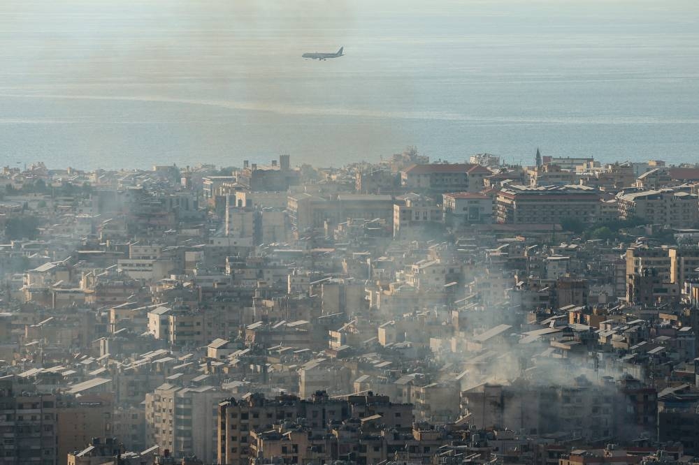 A plane approaches the city's airport, as smoke rises over Beirut's southern suburbs from a generator that caught fire, according to residents, as seen from Baabda, Beirut, on Saturday. REUTERS