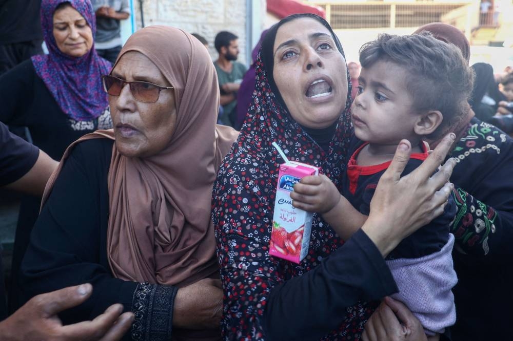 A Palestinian woman mourns relatives, killed in an Israeli strike on Al-Bureij refugee camp, during their funeral at the Al-Aqsa Martyrs hospital in Deir al-Balah in the central Gaza Strip on Sunday. AFP