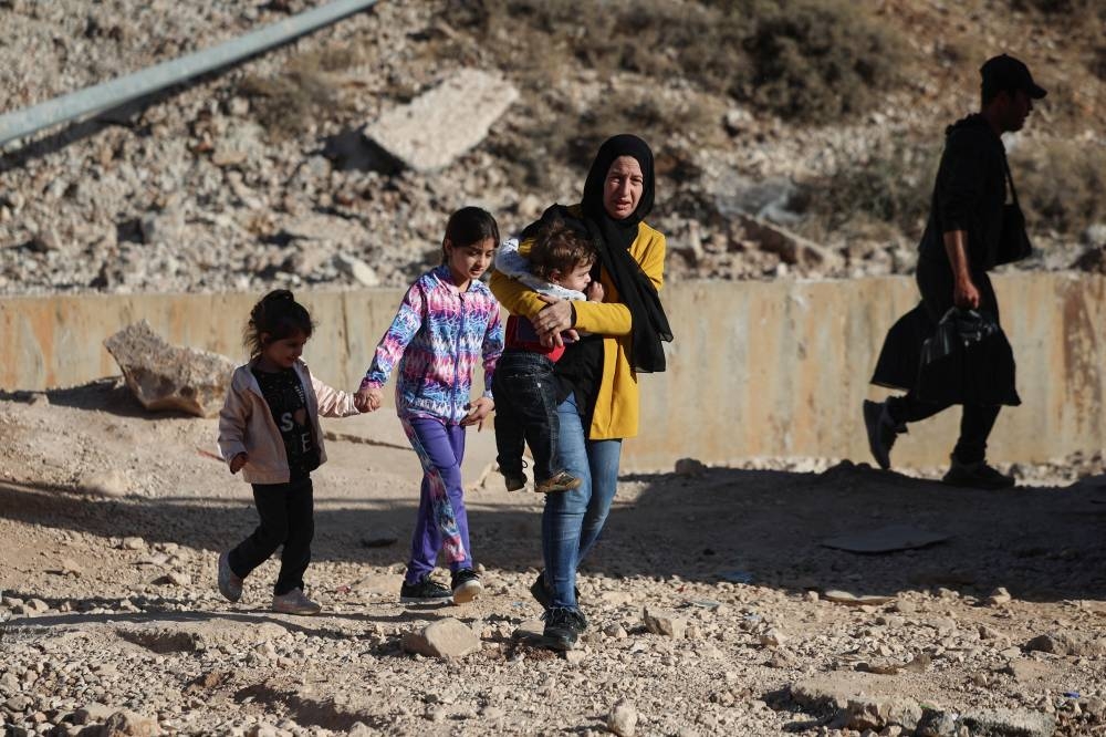 Lebanese Amal Tefayeli, from Baalbek, flees Lebanon to Syria on foot with her children at the Masnaa border crossing, on Monday. REUTERS