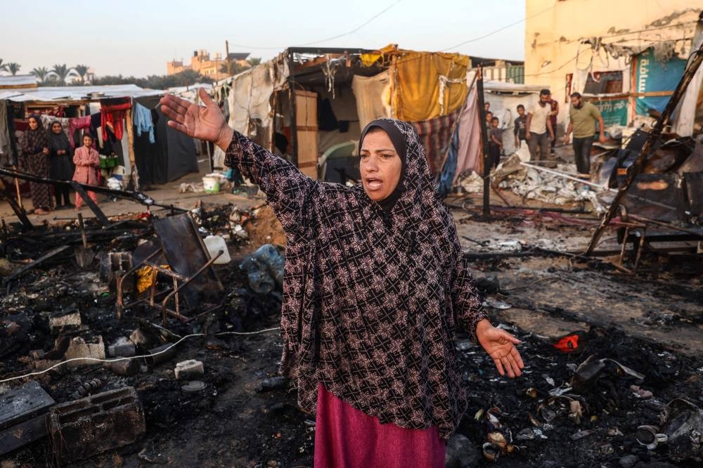 A Palestinian woman gestures as she checks the destruction following an Israeli army strike around tents for displaced people inside the walls of Al-Aqsa Martyrs Hospital in Deir al-Balah, in the central Gaza Strip, on Monday. AFP