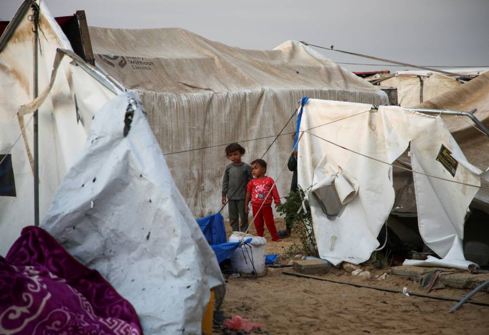 Children look on, as Palestinians inspect the damage at the site of an Israeli strike on a tent camp sheltering displaced people in Al-Mawasi area in Khan Younis, in the southern Gaza Strip, on Tuesday. REUTERS