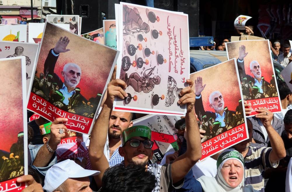 Demonstrators carry signs and pictures of late Hamas leader Yahya Sinwar during a protest in support of Lebanon and Gaza in Amman, Jordan on Friday. REUTERS