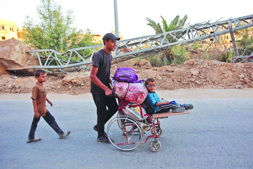 
Displaced Palestinians, ordered by the Israeli army to leave the school in Beit Lahia where they were sheltered, arrive in Gaza City, yesterday. 