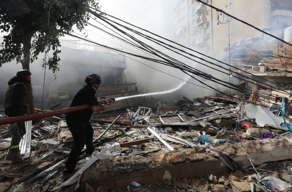 Civil defence members put out a fire at a damaged site, in the aftermath of Israeli strikes on Beirut's southern suburbs, on Sunday.