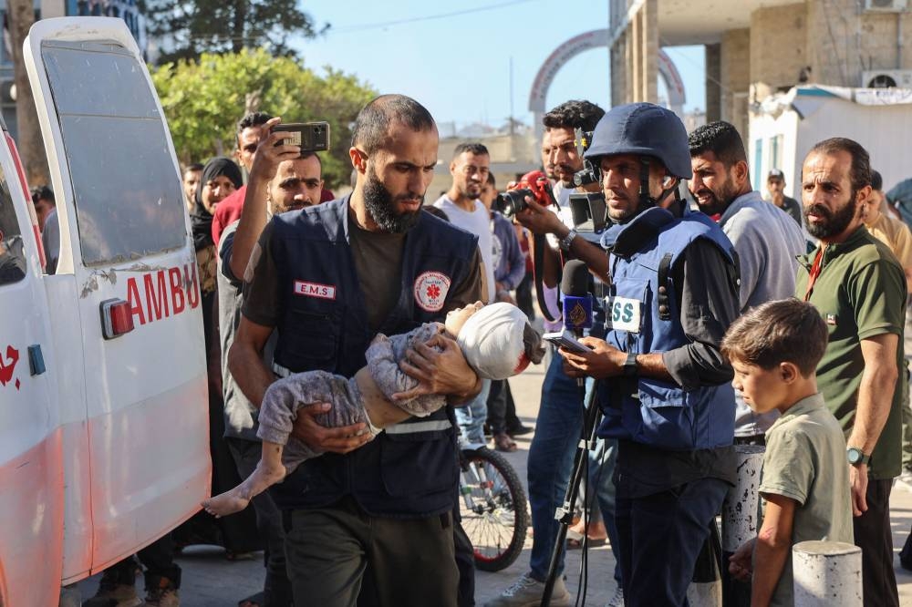 A Palestinian medic rushes a child injured in Israeli military operations in northern Gaza, into Al-Ahli Arab hospital, also known as the Baptist hospital in Gaza City, on Monday. AFP