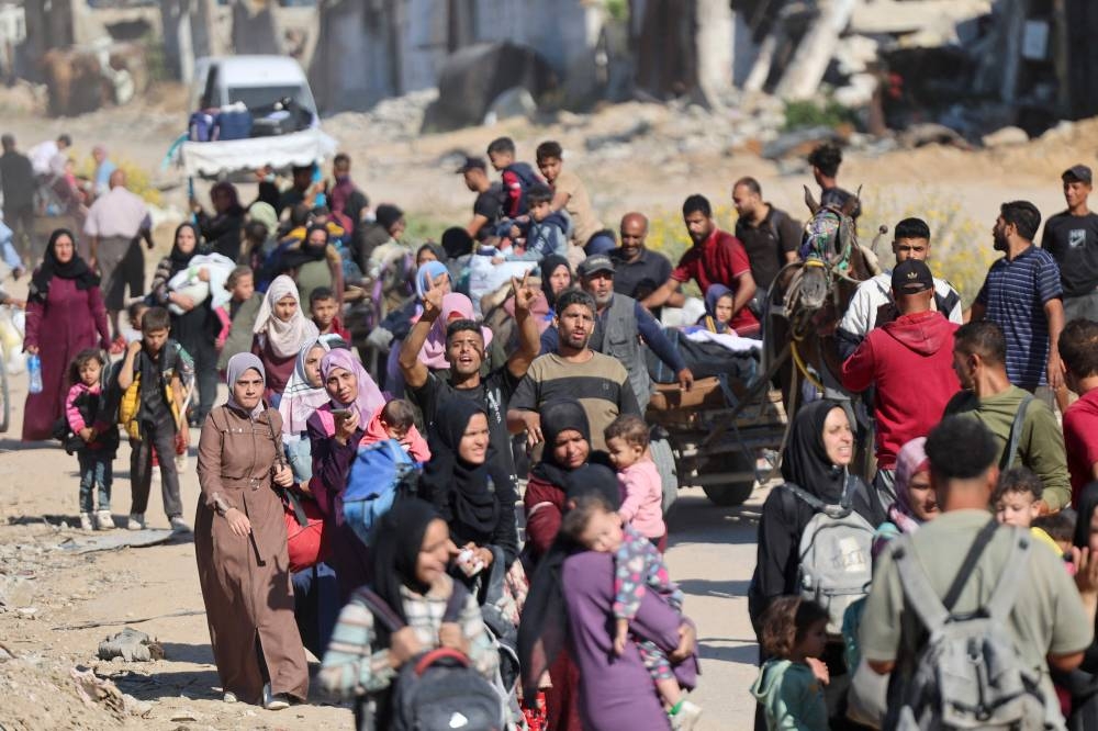 A man flashes the V for victory sign as displaced Palestinians fleeing Israeli military operations in Beit Lahia in the northern Gaza strip walk along the Salah al-Din main road in eastern Gaza City making their way to the city centre, on Tuesday. AFP
