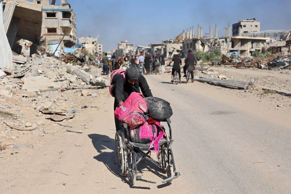 A woman pushing a wheel chair loaded with her personal belongings as displaced Palestinians fleeing Israeli military operations in Beit Lahia in the northern Gaza strip walk along the Salah al-Din main road in eastern Gaza City making their way to the city centre, on Tuesday. AFP