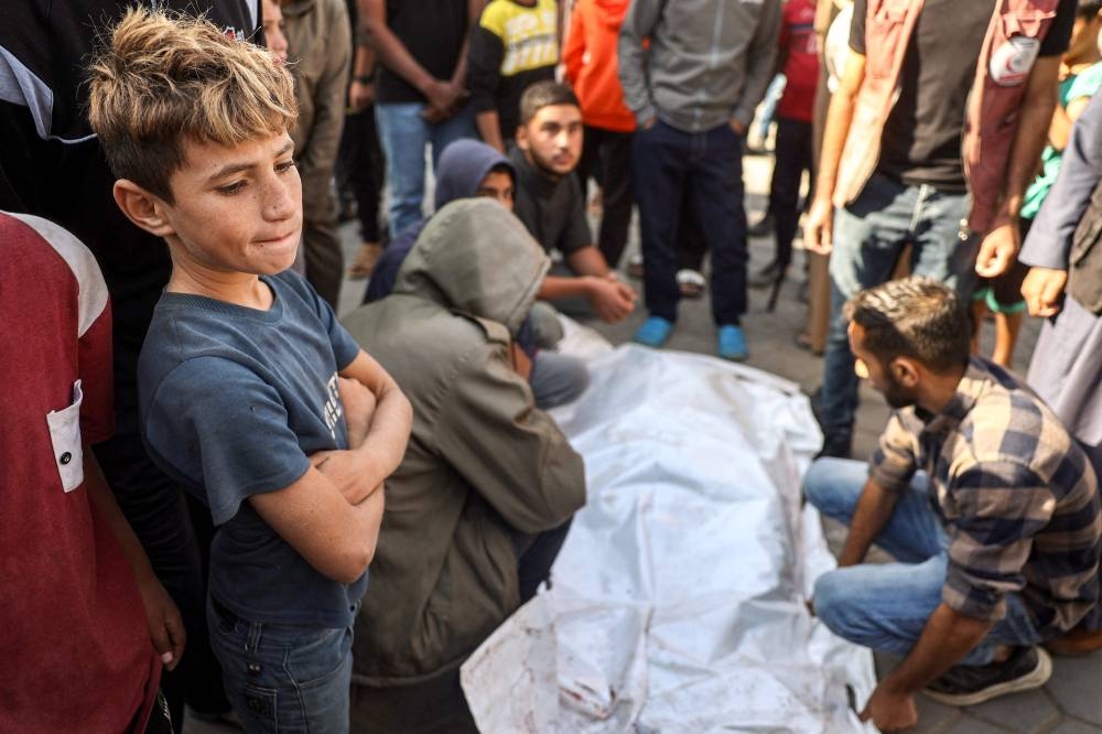 A boy reacts as mourners gather by one of the bodies of workers of the United Nations Relief and Works Agency for Palestine Refugees (UNRWA) who were killed earlier when their truck was reportedly hit by bombardment, during the funeral at the Aqsa Martyrs' Hospital in Deir el-Balah in the centre of the Gaza Strip Wednesday. AFP