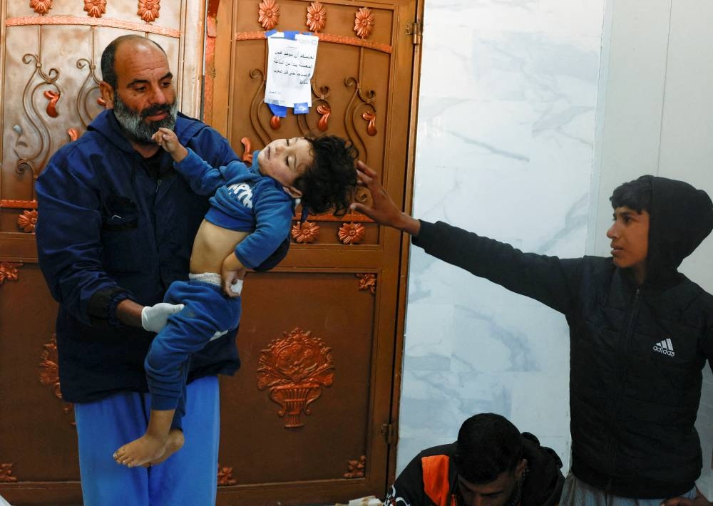 A boy reaches out towards the body of a Palestinian child killed in Israeli strikes, in Khan Younis in the southern Gaza Strip, on Friday. REUTERS