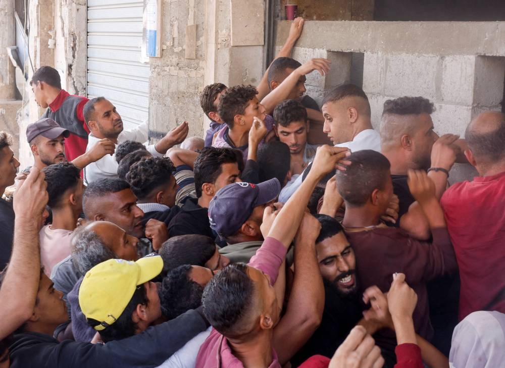 Palestinians gather to buy bread from a bakery, amid the Israel-Hamas conflict, in Khan Younis, southern Gaza Strip on Wednesday. REUTERS