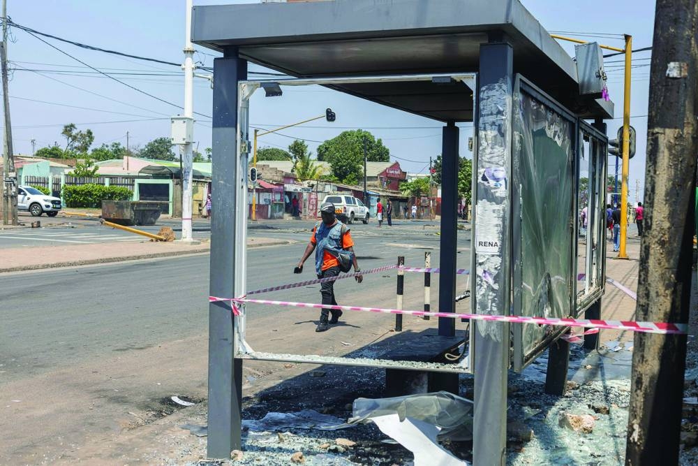 Residents walk past a damaged bus stop in Maputo.