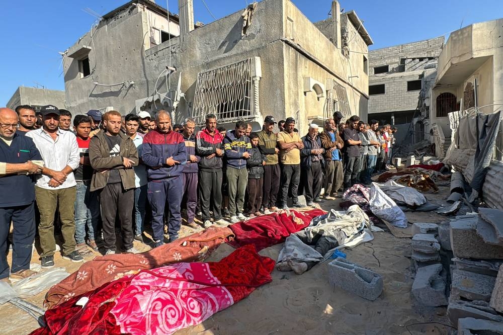 Palestinians pray over bodies of relatives, killed in an overnight Israeli airstrike, in Beit Lahia the northern Gaza Strip on Sunday. AFP