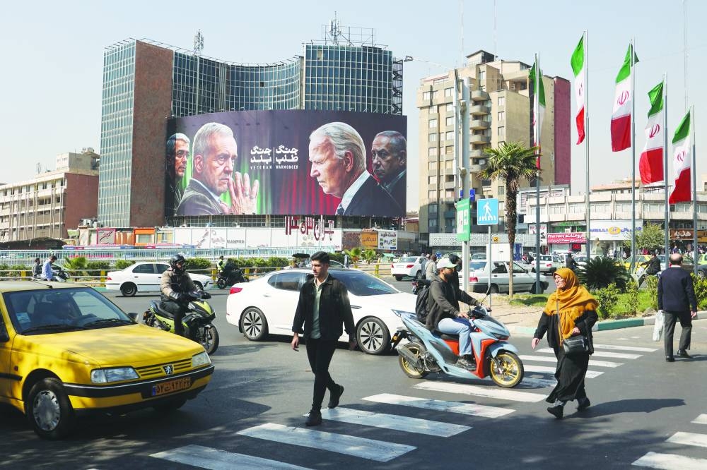 Iranians walk next to an anti-US and Israeli billboard on a street in Tehran.