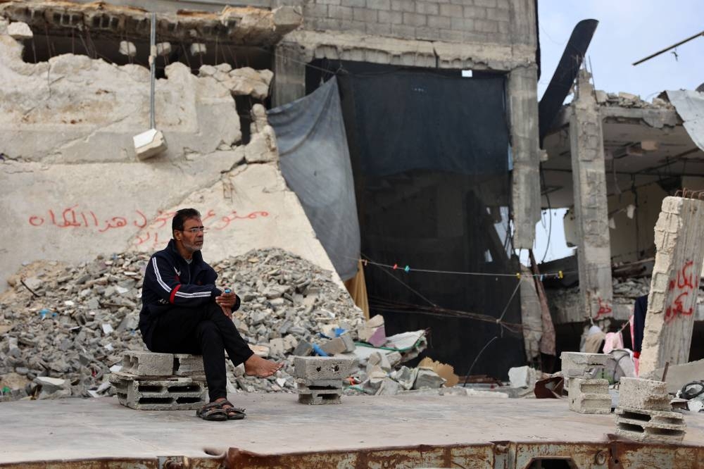 A displaced Palestinian man sits in front of his temporary shelter set up inside a destroyed building in Gaza City on Saturday. AFP