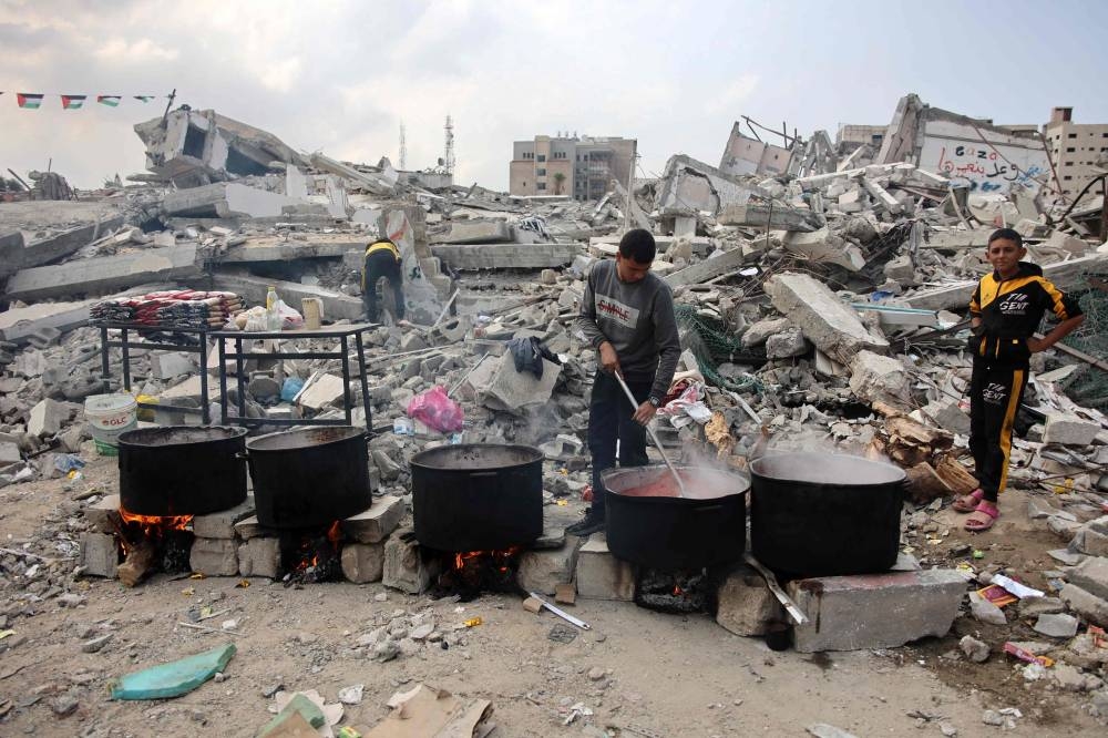 A man prepares meals to be distributed to displaced Palestinians in front of a levelled building in Gaza City on Saturday. AFP