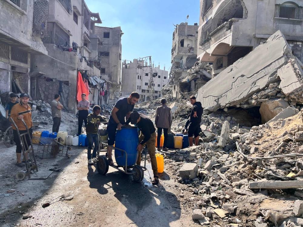 Palestinians fill containers with clean water in the midst of the devastation in Beit Lahia in the northern Gaza Strip on Sunday. AFP