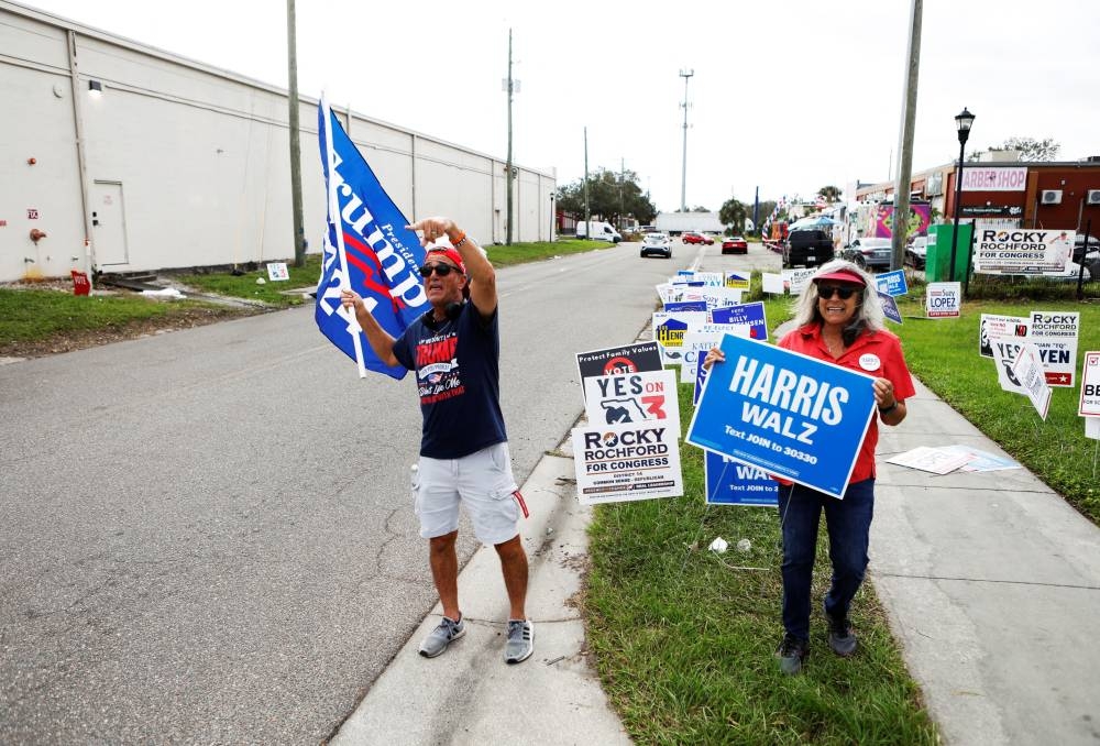 Robert Browning (L) and Terri Bieberbach wave campaign sings outside of a polling precinct on Election Day at the Town 'N Country Regional Public Library in Tampa, Florida, on Tuesday. REUTERS