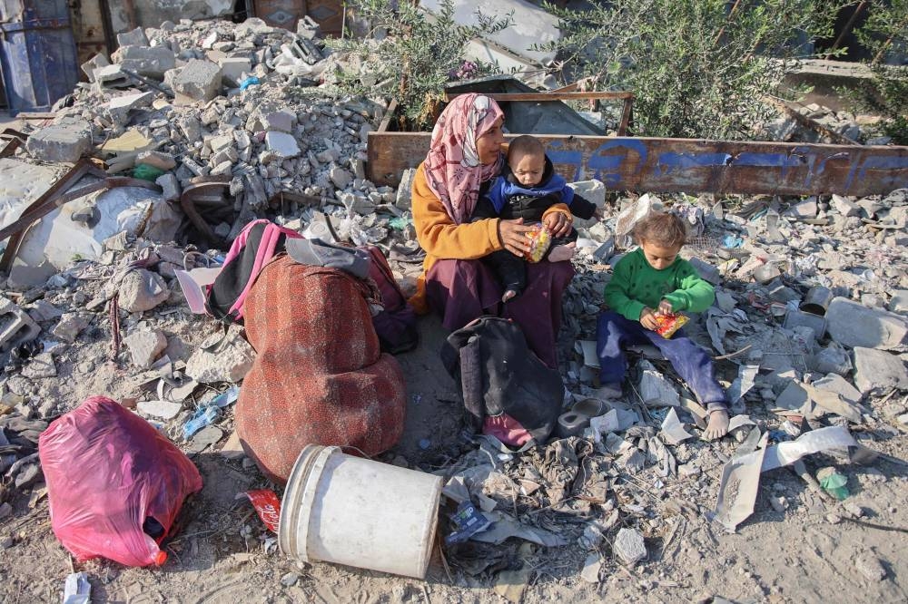 A woman rests with her children as displaced Palestinians flee Beit Lahia in the northern Gaza Strip, Tuesday.
