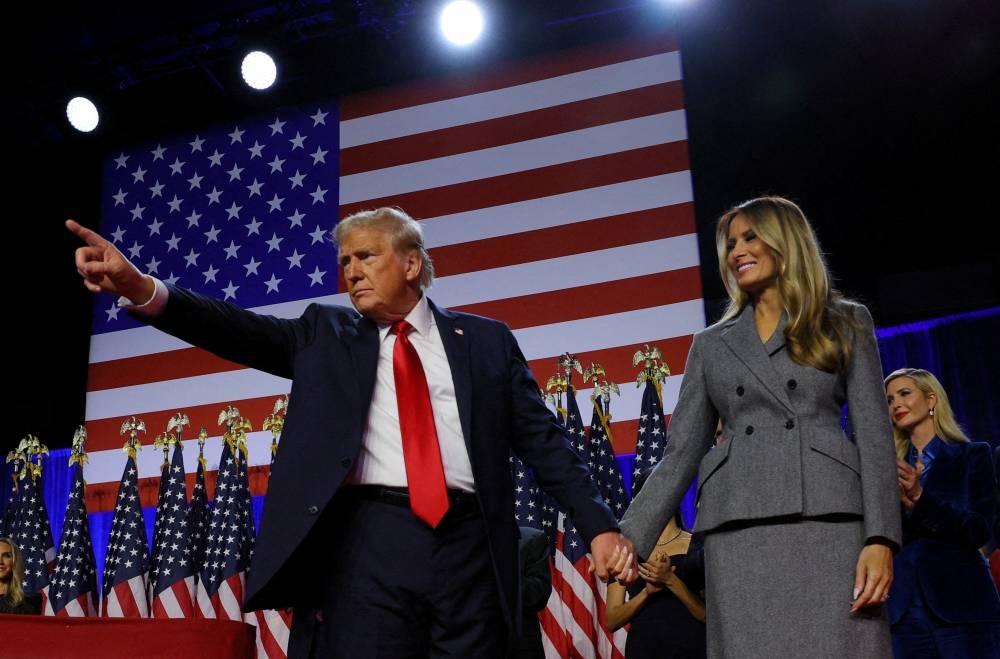 Republican presidential nominee and former U.S. President Donald Trump gestures as he holds hands with his wife Melania during his rally, at the Palm Beach County Convention Center in West Palm Beach, Florida, Wednesday.