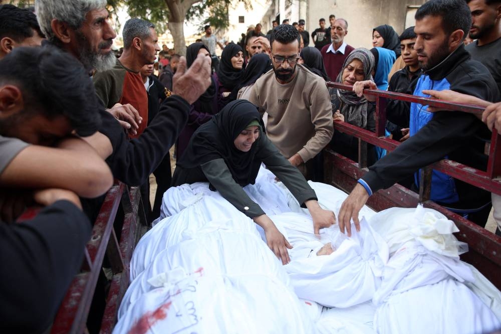 A woman reacts as Palestinians surround bodies lined up in the back of a pickup truck, in the courtyard of the al-Shifa hospital in Gaza City after the bodies of victims were transported there, following an Israeli strike that hit a school-turned-shelter in the Al-Shati refugee camp on Thursday. AFP