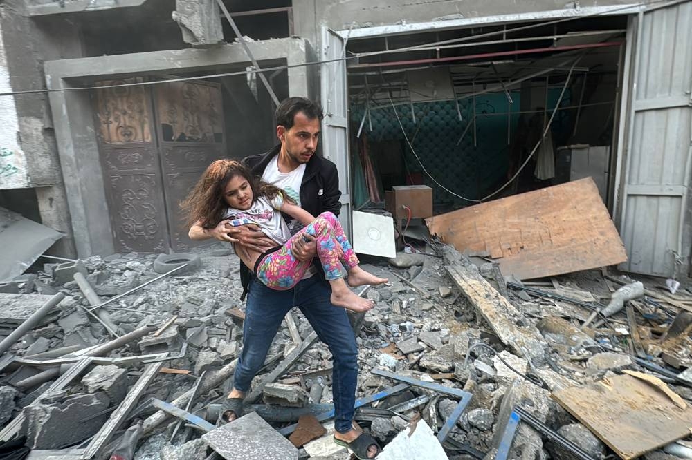 A Palestinian man carries away an injured child from a home that was hit in an Israeli strike on the Jabalia refugee camp in the northern Gaza Strip, on Thursday. AFP