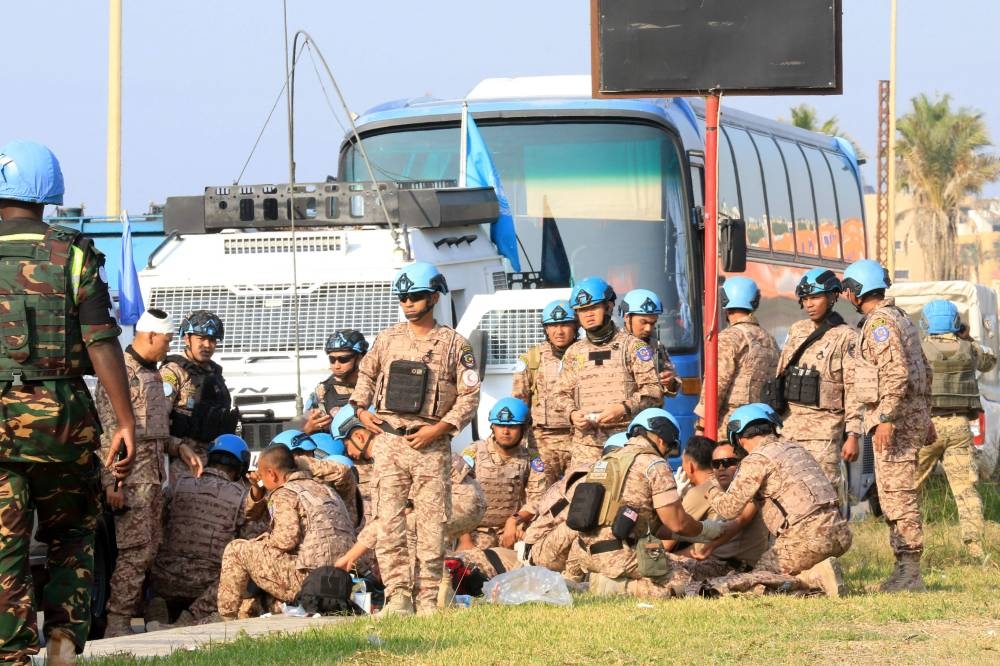 Members of the UNIFIL peacekeeping force sit on the side of a road at the site of an Israeli strike at the northern entrance of the southern city of Sidon, on Thursday. AFP