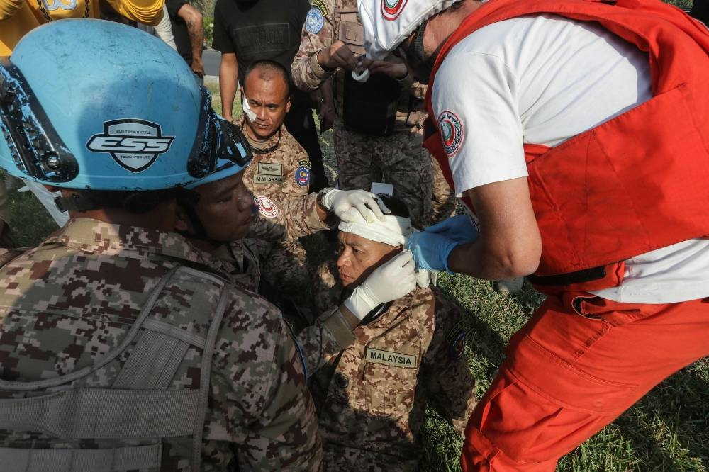 A rescuer and a member of the Malaysian battalion of the United Nations Interim Force In Lebanon (UNIFIL) treat the wound of a fellow soldier, after he was injured at the site of an Israeli airstrike at the northern entrance of the southern Lebanese city of Sidon, on Thursday. AFP