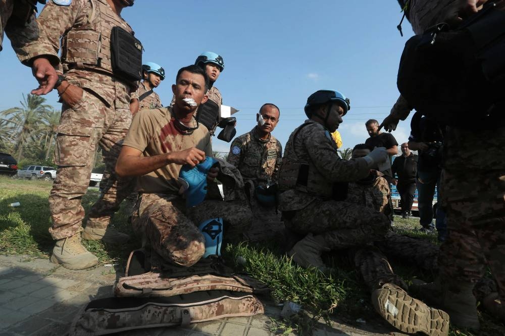 An injured member of the Malaysian battalion of the United Nations Interim Force In Lebanon (UNIFIL), sits on the ground after he was injured at the site of an Israeli airstrike at the northern entrance of the southern Lebanese city of Sidon, on Thursday. AFP