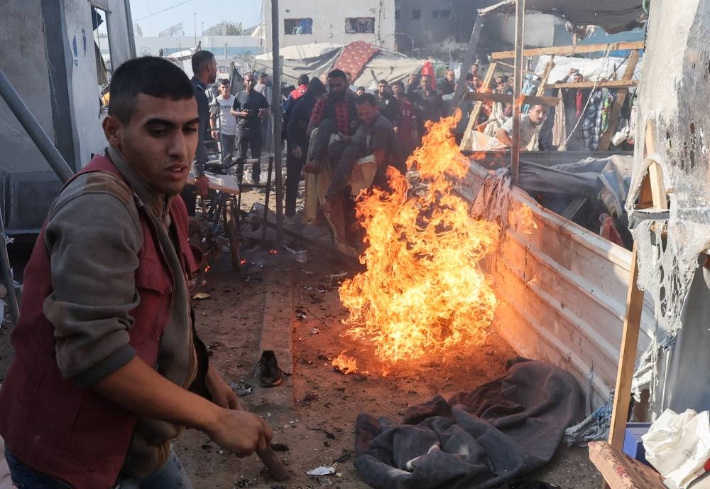 People carry a casualty near a fire at the site of an Israeli strike on a tent housing displaced people, at Al-Aqsa Martyrs Hospital in Deir Al-Balah, in the central Gaza Strip, on Saturday. REUTERS