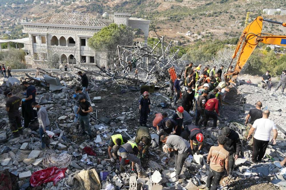 Rescuers use an excavator to search for survivors at the site of an Israeli airstrike that targeted the village of Almat north of Beirut, on Sunday. AFP