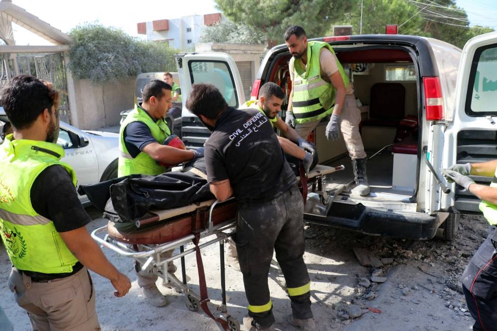 Rescuers with the Amal-linked Risala Scouts association evacuate the body of one of their colleagues, a day after an Israeli strike hit the organisation's headquarters in the southern Lebanese village of Deir Qanoun, reportedly killing at least six, on Sunday. AFP