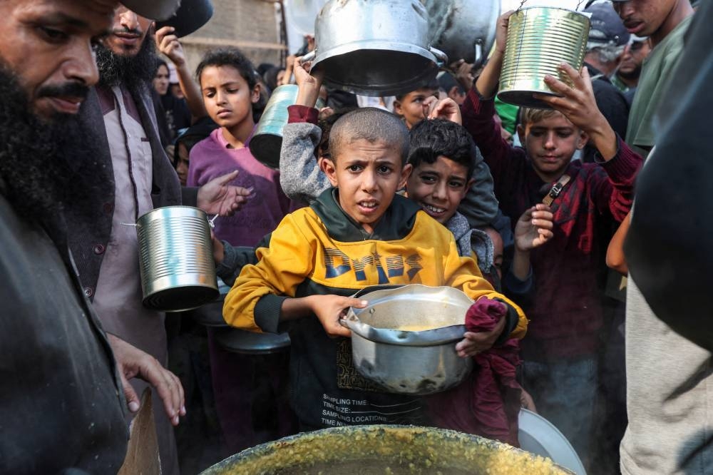 Palestinians gather to receive meals cooked by a charity kitchen, amid the ongoing conflict between Israel and Hamas, in Deir Al-Balah, in the central Gaza Strip, on Sunday. REUTERS 