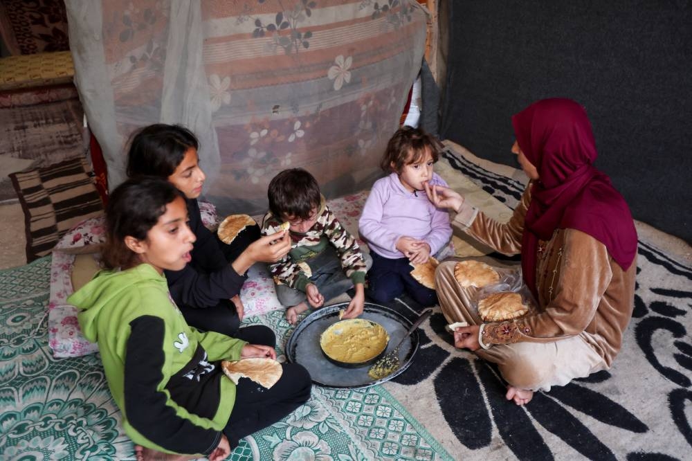 Itimad Al-Qanou, a displaced Palestinian mother from Jabalia, eats with her children inside a tent, amid Israel-Gaza conflict, in Deir Al-Balah, central Gaza Strip, Saturday. REUTERS