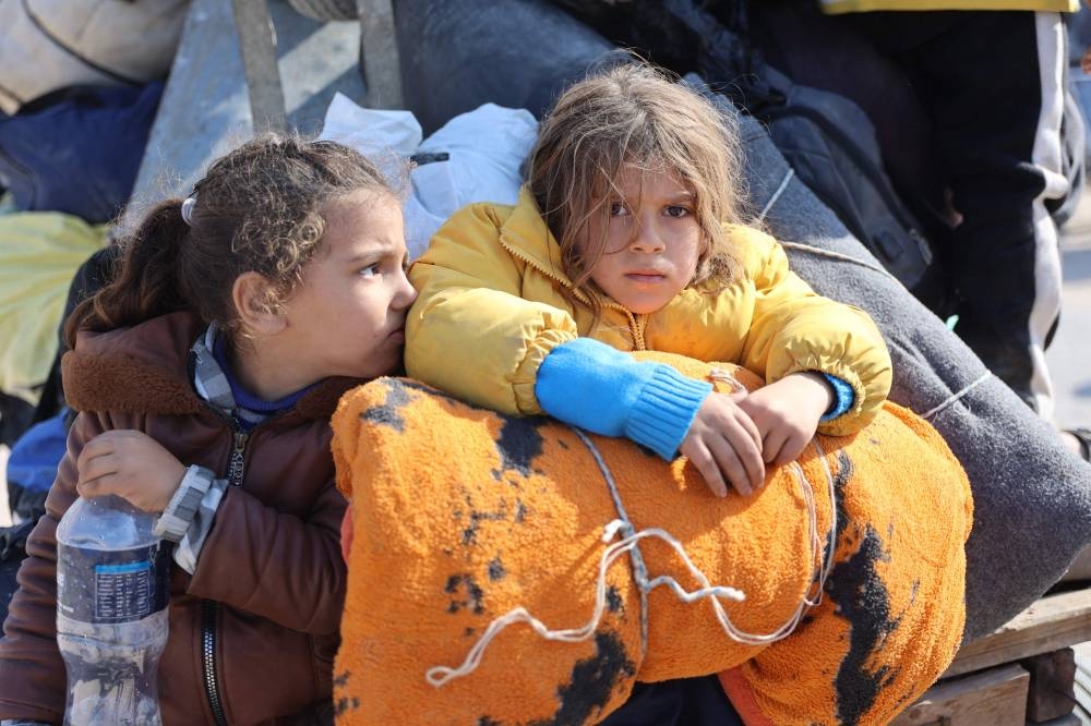Children sit in the back of a donkey cart as Palestinians displaced from shelters in Beit Hanoun cross the main Salaheddine road into Jabalia in the northern Gaza Strip following Israeli army evacuation orders, on Tuesday. AFP
