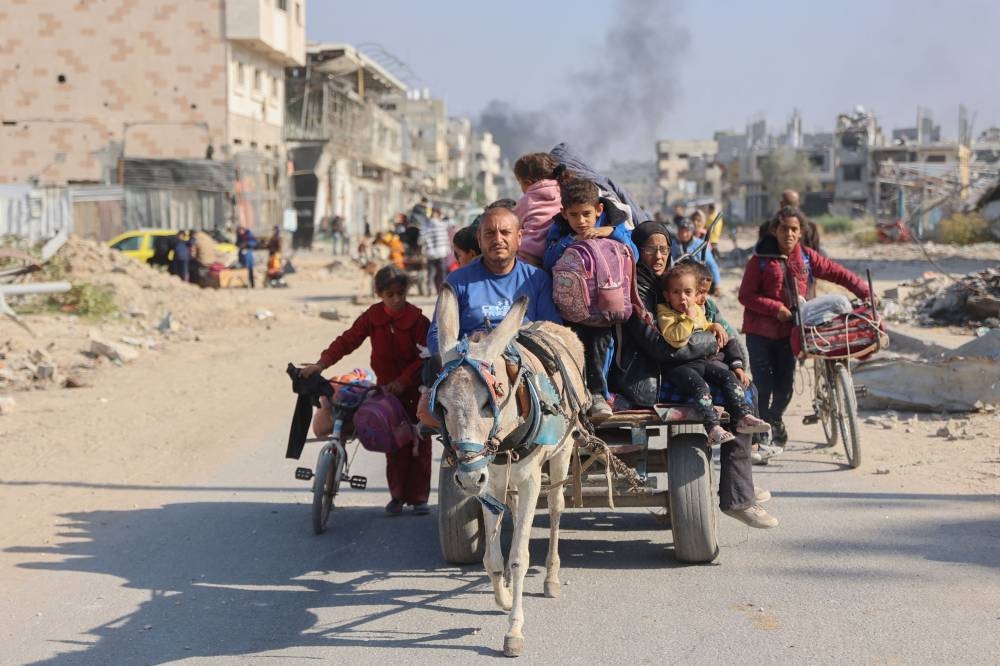 Palestinians displaced from shelters in Beit Hanoun cross the main Salaheddine road into Jabalia in the northern Gaza Strip on bicycles and donkey carts following Israeli army evacuation orders, on Tuesday. AFP
