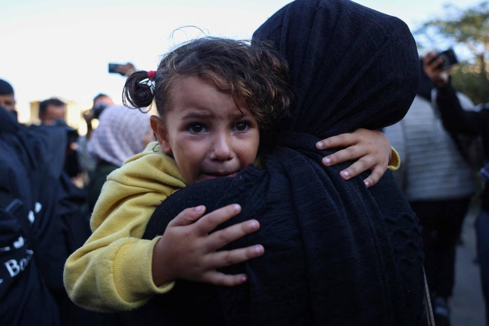 A girl cries as she's carried by a Palestinian woman mourning relatives killed in overnight Israeli strikes on the al-Mawasi cafeteria in southern Gaza's Khan Yunis, outside Nasser hospital, on Tuesday. AFP