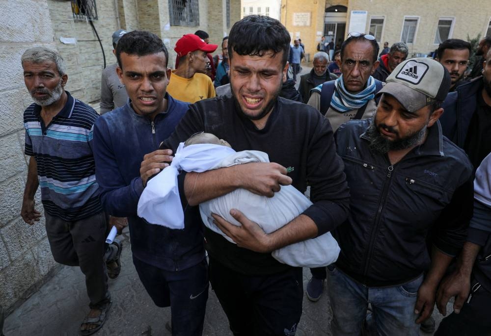 A man carries the body of Palestinian baby Ahmed Erheem, who medics said was killed in an Israeli strike, in Gaza City, on Wednesday. REUTERS