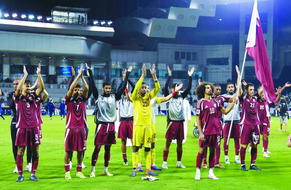 Star striker Akram Afif holds the Qatar flag as he celebrates with teammates after Al Annabi’s thrilling victory over Uzbekistan in the 2026 World Cup qualifying match at the Jassim Bin Hamad Stadium Thursday. PICTURES: Noushad Thekkayil
