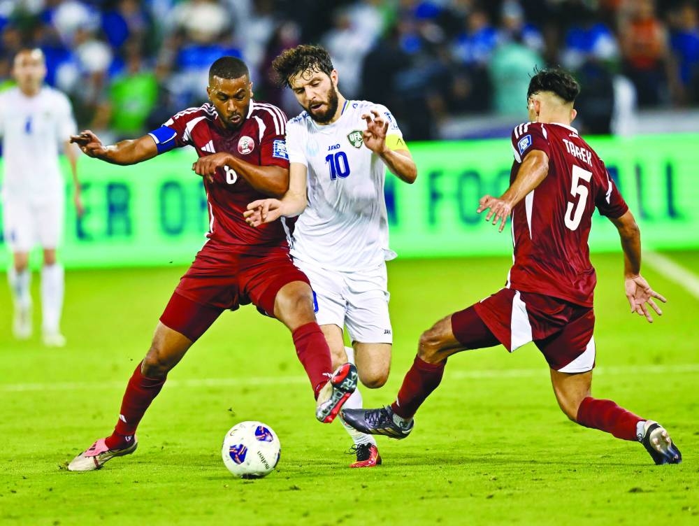 
Qatar’s Abdulaziz Hatem (left) and Tarek Salman fight for the ball with Uzbekistan’s Jaloliddin Masharipov. 