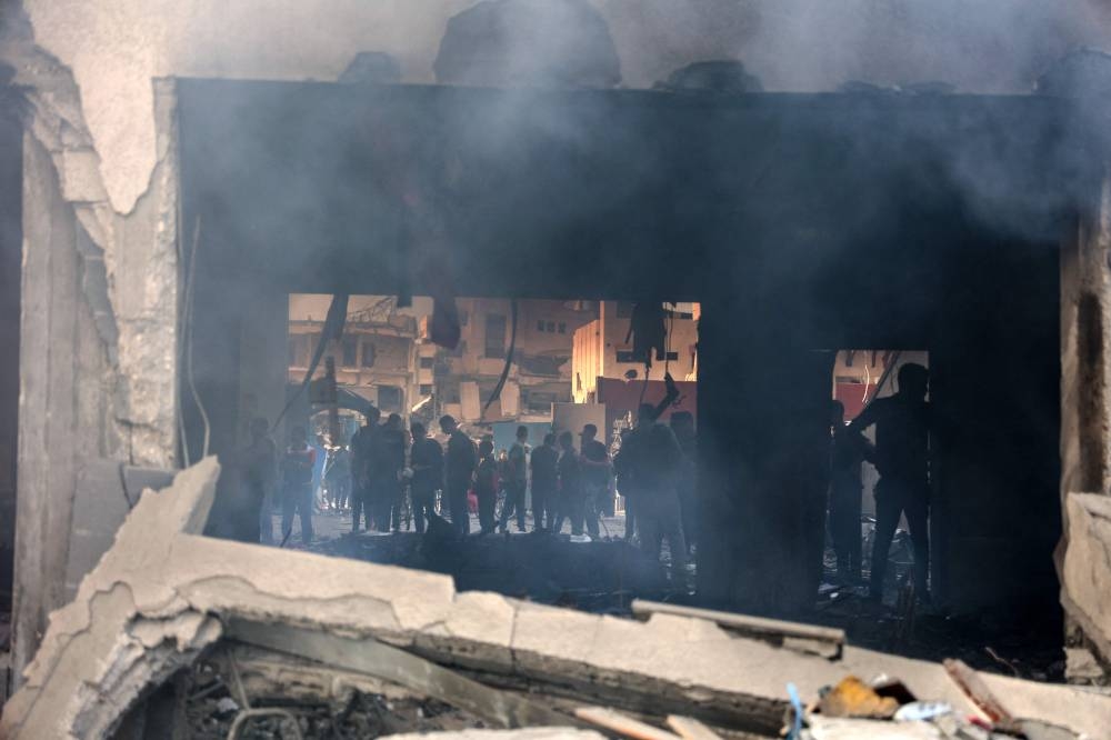People gather as smoke rises from a UN school-turned-shelter after it was hit in an Israeli strike, in the Rimal neighbourhood of Gaza City in the northern Gaza Strip on Thursday. AFP