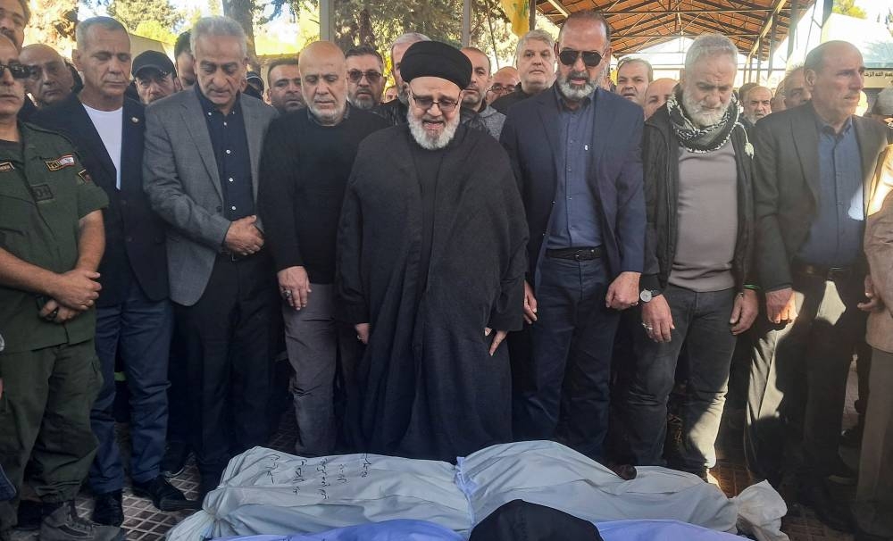 Mourners pray near the bodies of three civil defence members who were killed during an Israeli strike that hit a civil defence centre in Baalbek on Thursday, during their funeral, Lebanon, on Saturday. REUTERS